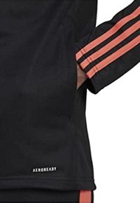 Top sportivo nero con tre strisce rosa e nere sulle maniche. Logo "AEROREADY" posizionato vicino all'orlo. Texture liscia.