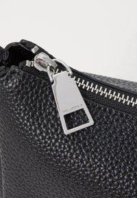 Borsa in pelle nera dal texture leggero con zip e accessori in argento, dotata di una linguetta rettangolare della zip con la scritta "KARL LAGERFELD" in rilievo.