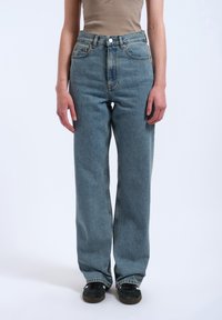 Light blue high-waisted jeans in a loose fit, made from denim with a faded texture, featuring a button closure and five pockets.