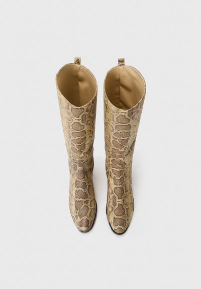Beżowe kozaki do kolan z wzorem wężowej skóry, gładką fakturą, spiczastym noskiem i widoczną podszewką wewnętrzną, wyposażone w pętelki do ściągania na górze.