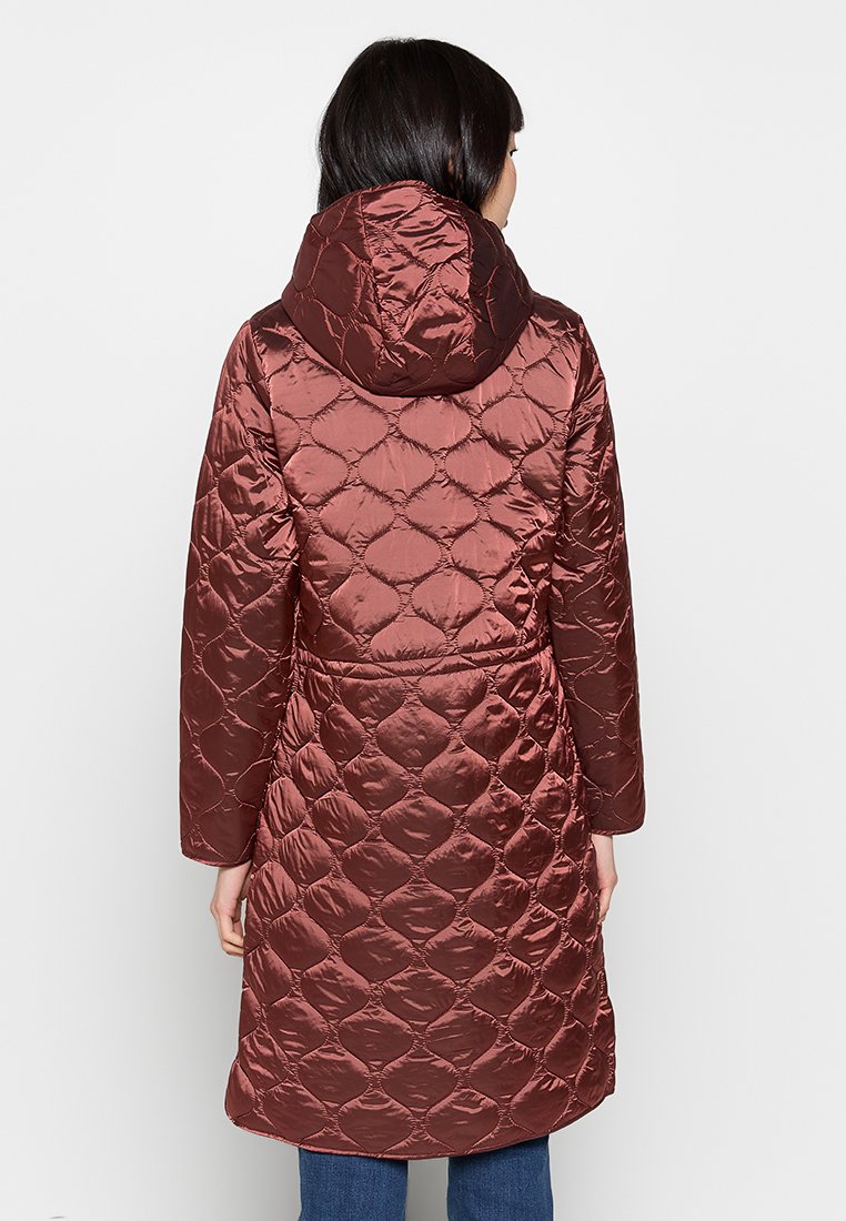 Gevoerde jas in een diepe rode kleur met een gewatteerd ruitpatroon, voorzien van een capuchon en een geplooide taille, lange mouwen en een middellange snit.