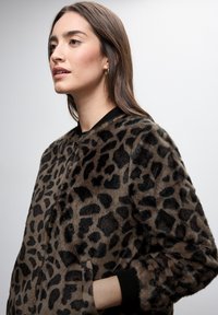 Leopard print bomber jacket in soft faux fur. Features ribbed cuffs and collar, zip closure, and a relaxed fit. Shades of brown and black.