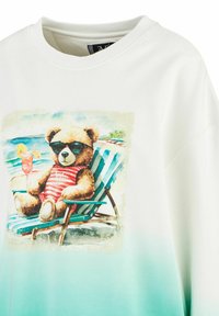 Weißes Sweatshirt mit einem bedruckten Teddy-Bären in Sonnenbrille, der in einem gestreiften Liegestuhl entspannt, mit einem gradienten türkisen Saum.