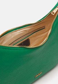 Borsa a tracolla verde in pelle con zip dorata, interno in tessuto beige, presenta una piccola tasca e il logo del marchio sulla parte esterna.