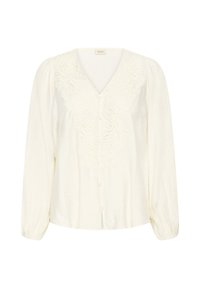 Blouse blanche à manches longues avec col en V, broderie florale discrète sur le devant, fermeture par boutons et poignets froncés.