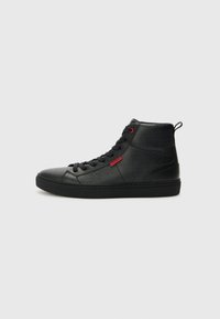 Baskets montantes noires en cuir lisse, avec une texture à motifs, des accents rouges et des lacets noirs sur une semelle rembourrée.