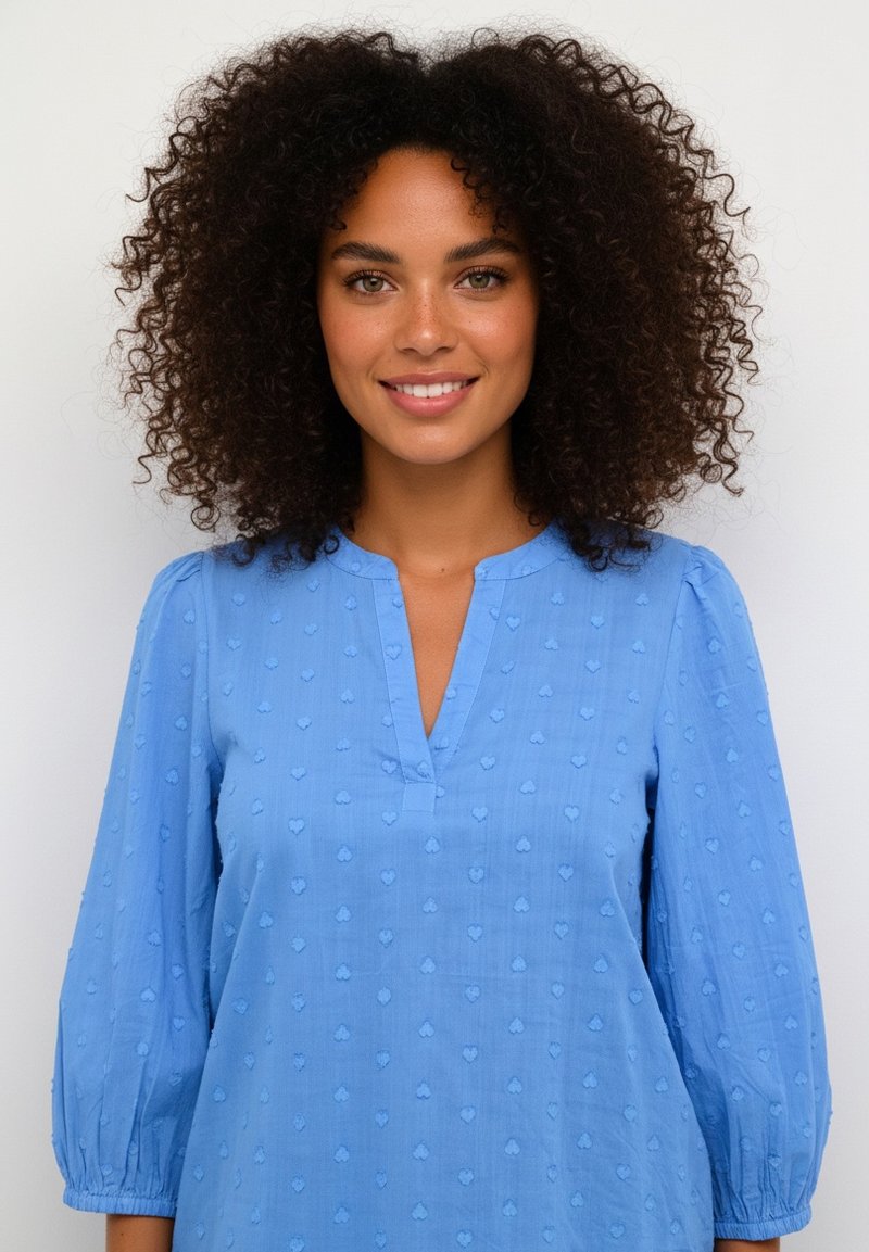 Svetlomodrá blúzka s výstrihom do V a tromi štvrťovými rukávmi s nariasením, s textúrovaným vzorom malých srdiečok po celej ploche.