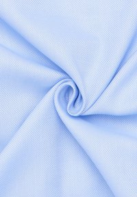 Lichtblauw geweven stof met een gestructureerde oppervlakte, getoond in een opgerolde opstelling, die de flexibiliteit en het patroon van het materiaal benadrukt.