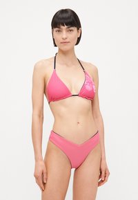 Pink bikini set featuring a triangular top with adjustable straps and a v-shaped bottom, made from a smooth, stretchy fabric.
