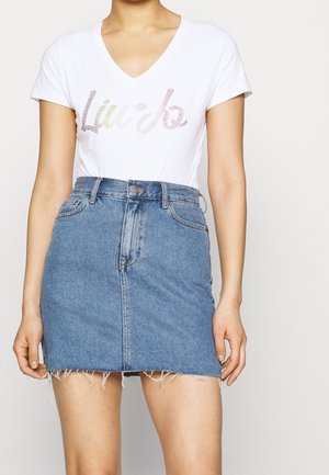Biała koszulka typu V-neck z multikolorowym napisem z kryształków "Liu Jo" w zestawie z jasnoniebieską mini spódnicą dżinsową z postrzępionym dołem.