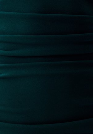 Donkergroene stof met een gladde textuur, voorzien van horizontale plooien die een aansluitend ontwerp creëren. Zacht, rekbaar materiaal met een egale kleur.