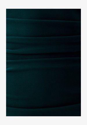 Donkergroene stof met een gladde textuur, voorzien van horizontale plooien die een aansluitend ontwerp creëren. Zacht, rekbaar materiaal met een egale kleur.