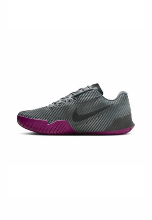Gray athletic shoe with vertical ridges, black accents, and a purple outsole. Features a rounded toe and lacing system.
