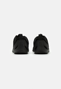 Czarne buty sportowe z siateczkową cholewką, amortyzowaną podeszwą i pętlą z tyłu. Minimalistyczny design bez widocznych logo.