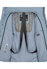 Intérieur d'une veste bleu clair montrant des bretelles noires, un panneau arrière en mesh, une fermeture éclair, des boutons-pression et une étiquette de température sur la manche.