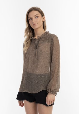 Transparente braune Bluse mit floralem Muster, Rüschenausschnitt, Bindeschluss und elastischen Ärmelbündchen, kombiniert mit dunklen Shorts.