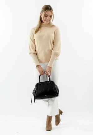 Schwarze Lederhandtasche mit abgerundeten Obergriffen, Reißverschluss und subtiler Logodetail. Getragen mit beigem geripptem Pullover und weißen Jeans.