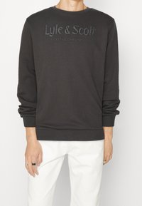 Mörkgrå sweatshirt med rund hals och långa ärmar. Har präglad text "Lyle & Scott" och detaljerna "ETABLERAD 1874".