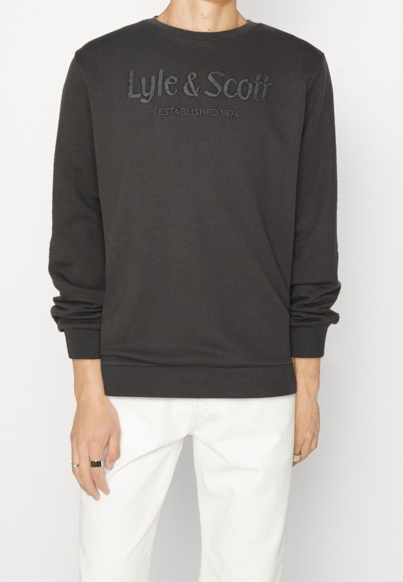 Mörkgrå sweatshirt med rund hals och långa ärmar. Har präglad text "Lyle & Scott" och detaljerna "ETABLERAD 1874".