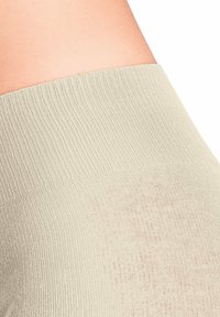 Ceinture côtelée beige clair d'un vêtement, présentant une finition texturée et une apparence lisse, offrant un look ajusté et confortable.