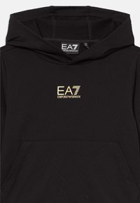 Čierna mikina s kapucňou vyrobená z jemného materiálu, vybavená klokankovou kapsou. Na hrudi sa nachádza zlaté logo EA7 Emporio Armani.