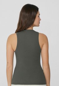 Dunkelolivgrünes, geripptes Tanktop mit tailliertem Design, runder Ausschnitt und ärmellosem Schnitt, der eine glatte Textur und minimale Details zeigt.