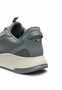 Szary tenisówka z teksturowaną cholewką, skórzanymi akcentami, wyściełanym kołnierzem i grubą białą gumową podeszwą z paskowanymi detalami.