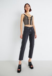 Cropped gray lace-up top with black accents, paired with dark gray straight-leg jeans and black platform sandals with an open toe.