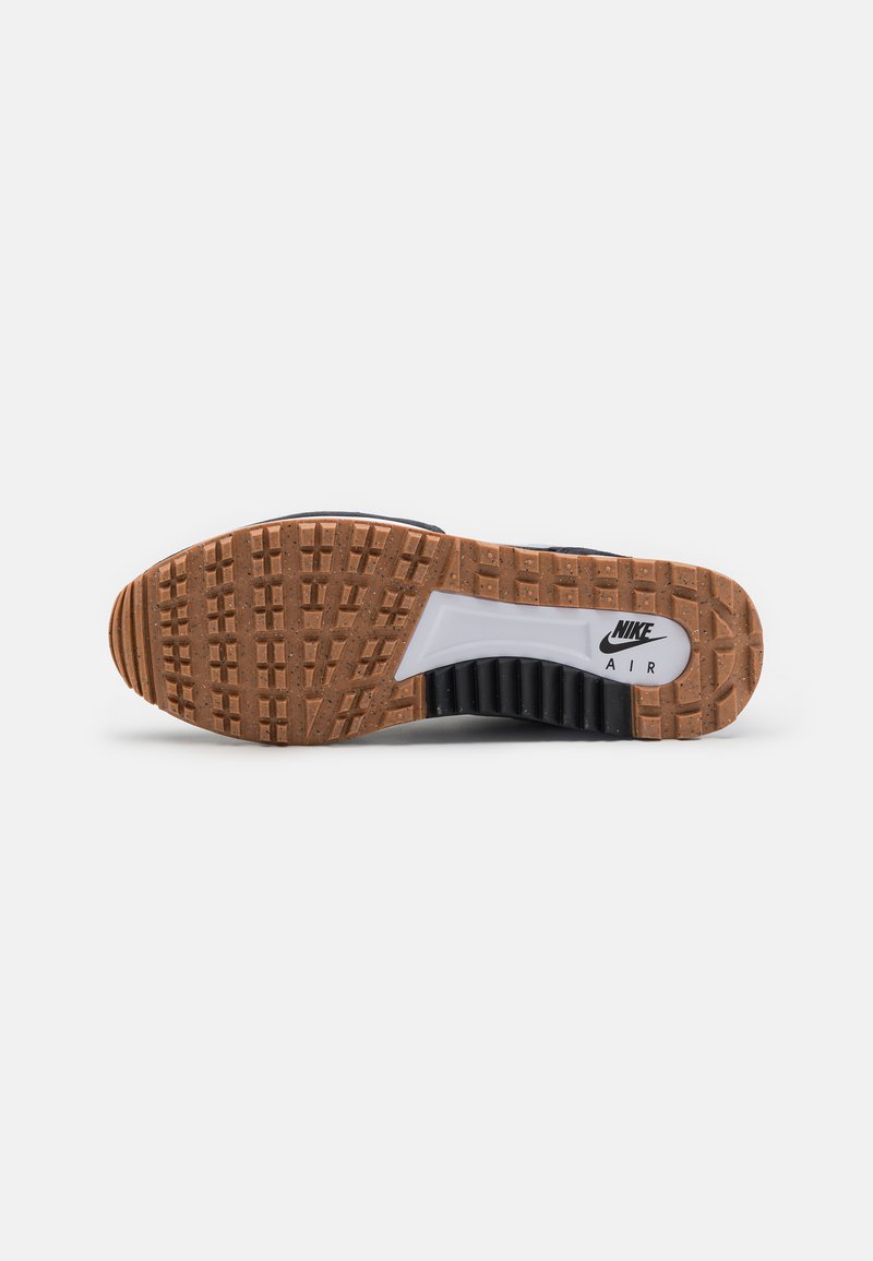 Nike Air sneaker featuring a textured brown rubber outsole with a white midsole and distinct tread patterns. Black upper offers stability.