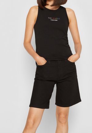Czarny top na ramiączkach z napisem "TO JEST MIŁOŚĆ" i logo Calvin Klein, zestawiony z czarnymi krótkimi spodenkami jeansowymi. Eleganckie dopasowanie o minimalistycznym designie.