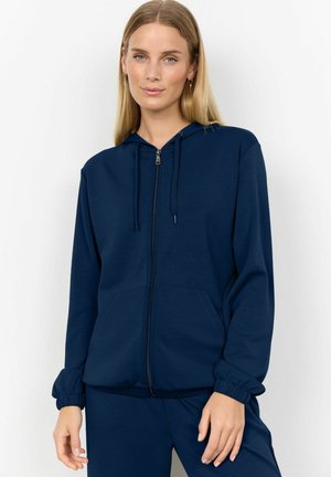 Hoodie zippé bleu marine avec capuche à cordon ajustable, poches avant et poignets élastiques. Texture lisse, coupe décontractée, idéale pour le superposition.