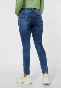 Smala blå denimjeans med en blekt tvätt, som har två bakfickor och midjehöjd, i kombination med ljusa sneakers.