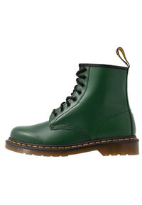 Green lace-up ankle boot made of smooth synthetic material with black accents, yellow stitching, and a pull tab at the heel.