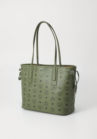 Zielona skórzana torba tote z tłoczonym wzorem loga MCM, z dwiema rączkami, subtelną teksturą oraz pojedynczym odpinanym paskiem dla większej wszechstronności.