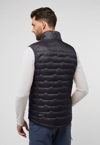 Schwarze Steppweste mit hohem Kragen und gestepptem Muster, aus glattem Material gefertigt. Auffälliges Logo-Detail am Saum.
