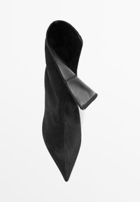 Černá špičatá toe bota s měkkým semišovým vnějškem a hladkým koženým vnitřkem. Má elegantní, minimalistický design a žádný viditelný hardwar.