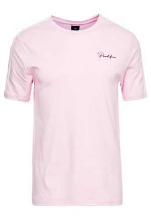 Jasnoróżowy t-shirt z krótkim rękawem i okrągłym dekoltem, z małym czerwono-czarnym logotypem w formie pisma na lewej górnej części klatki piersiowej.