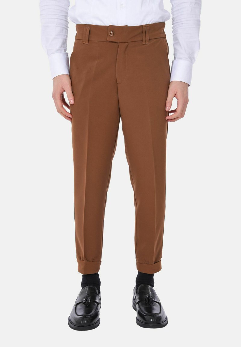 Pantaloni marroni su misura con frontale piatto, passanti per cintura e chiusura a singolo bottone. Il tessuto ha una texture liscia; i polsini sono arrotolati.