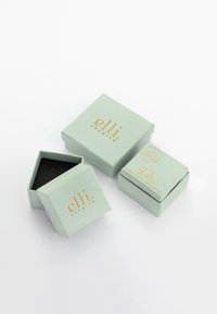 Mintgrønne smykkeskrin med guldfarvet branding, der har en mat overflade, en firkantet form, og et skrin der er delvist åbent for at afsløre en sort indvendig.