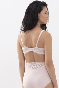 Vaaleanpunainen pitsinen bralette, jossa on säädettävät olkaimet, koristeena aaltoilevat reunat ja kukkakuviot. Pehmeä ja sileä materiaali täydentää pitsin reunusta.