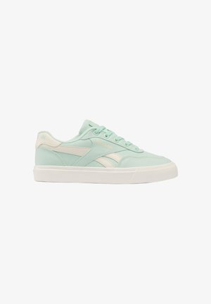 Lichtgroene en witte Reebok lage sneakers met vetersluiting en rubberen zool, zijaanzicht op een witte achtergrond.