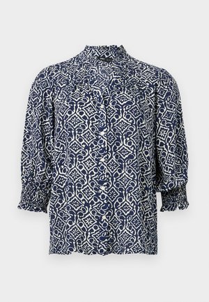 Laivastonsininen napillinen pusero, jossa valkoinen kukkakuvio ja geometrinen kuvio, kolme neljäsosaa hihoista, resorit mukautuvat ranteeseen ja röyhelöinen korkea kaulus.