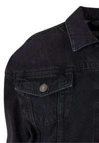 Zwarte denimjas met een puntschoenkragen, zilveren knopen en twee borstzakken met kleppen. Subtiele textuur zichtbaar.