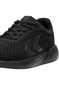 Chaussure de sport noire avec une tige en mesh texturé, des lacets, une semelle coussinée et deux logos chevrons gris foncé inclinés sur le côté.
