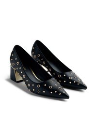 Chaussures à talons hauts en cuir noir avec un bout pointu, décorées de œillets en métal doré, dotées d'un accent métallique massif sur le talon.