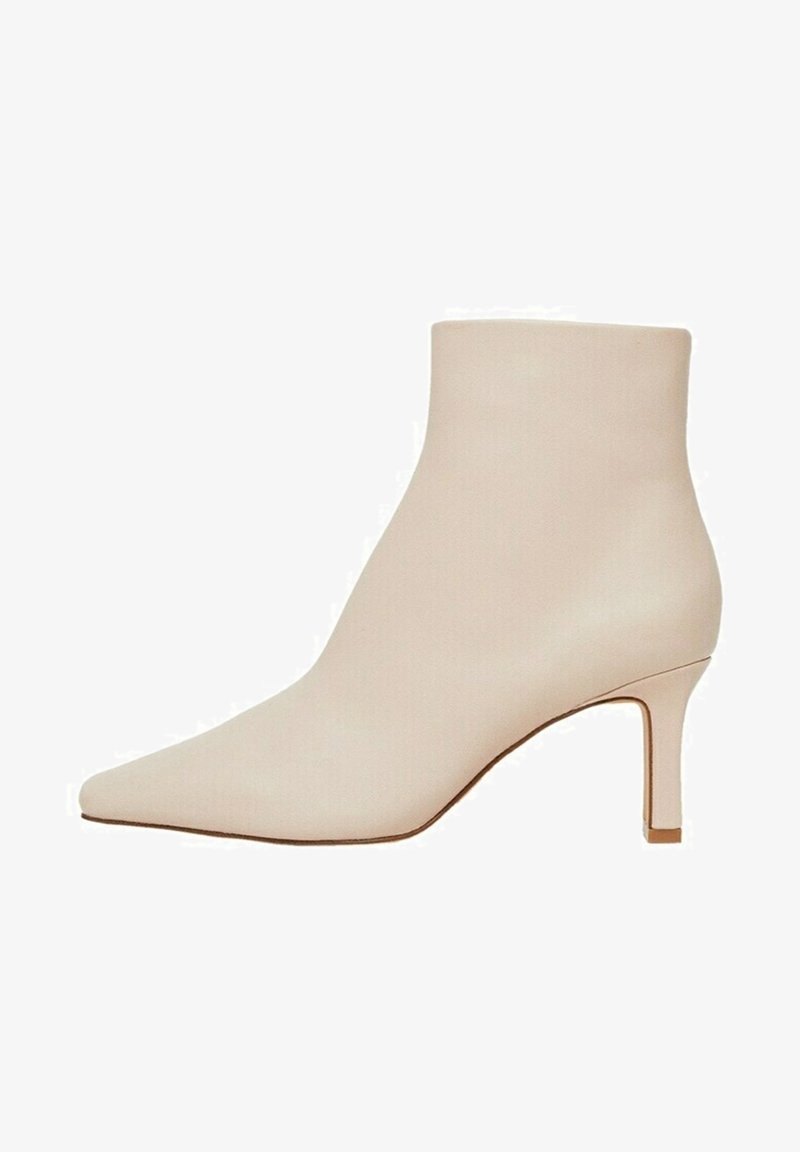 Bottine en cuir beige avec bout pointu et talon mi-hauteur élancé, texture lisse, design moderne minimaliste.