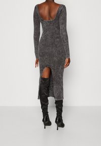 Szara, prążkowana sukienka z długim rękawem i niskim dekoltem z tyłu oraz bocznym rozporkiem, połączona z czarnymi, wysokimi kozakami do uda i szpilkami.