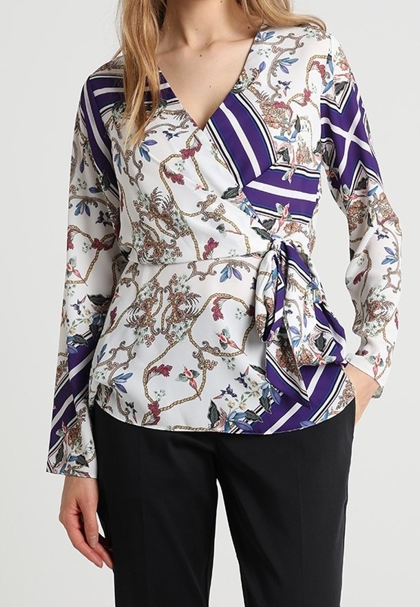 Top avvolgente in tessuto leggero con motivi floreali e geometrici in viola e bianco, con dettaglio a cravatta in vita e maniche lunghe.