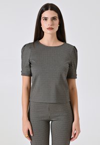 Top a scacchi bianco e nero con maniche corte a sbuffo, scollatura tonda, tessuto testurizzato, design aderente, abbinato a pantaloni a vita alta coordinati.