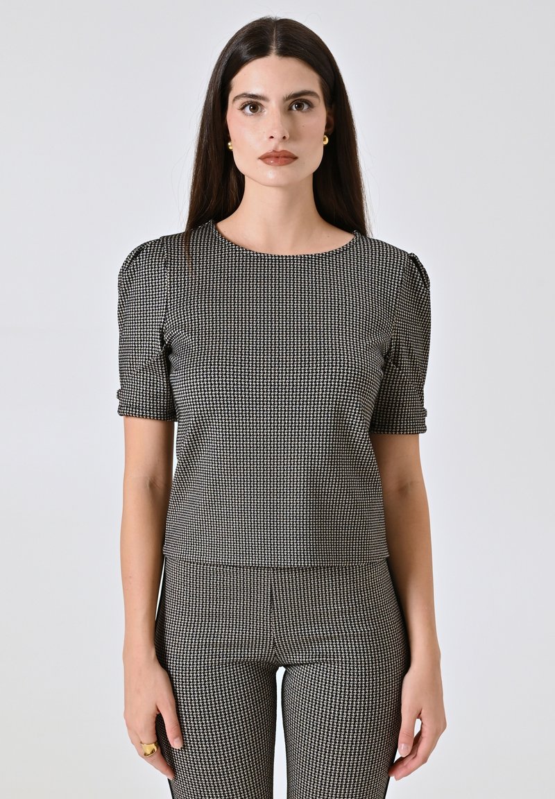 Top a scacchi bianco e nero con maniche corte a sbuffo, scollatura tonda, tessuto testurizzato, design aderente, abbinato a pantaloni a vita alta coordinati.